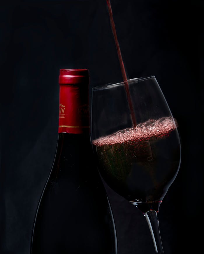 services-03 Elegant red wine pouring into a glass with a bottle in background, perfect for wine enthusiasts.